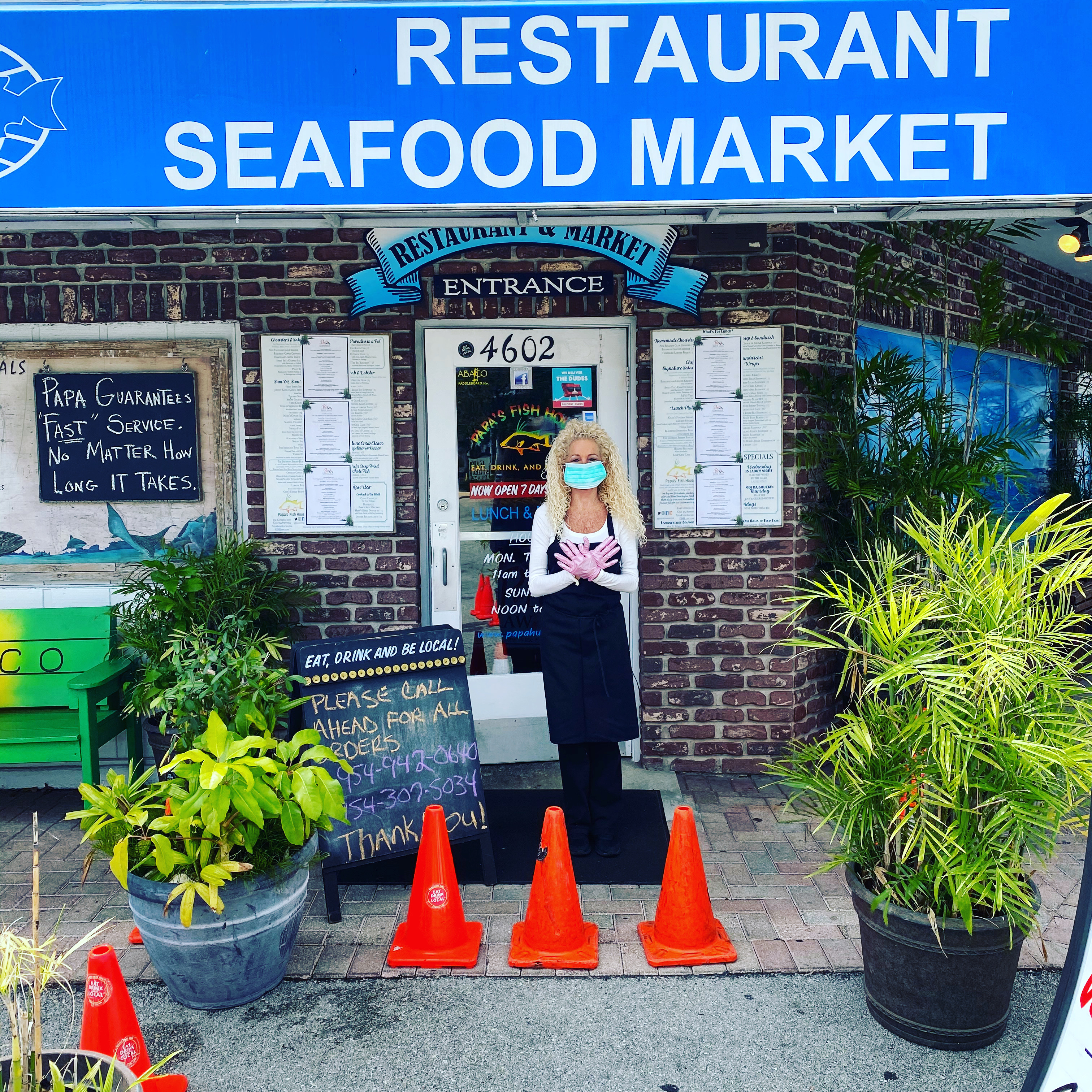 Employee in mask and gloves in front of Seafood World