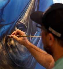 Dennis Friel paints details on a fish mural.