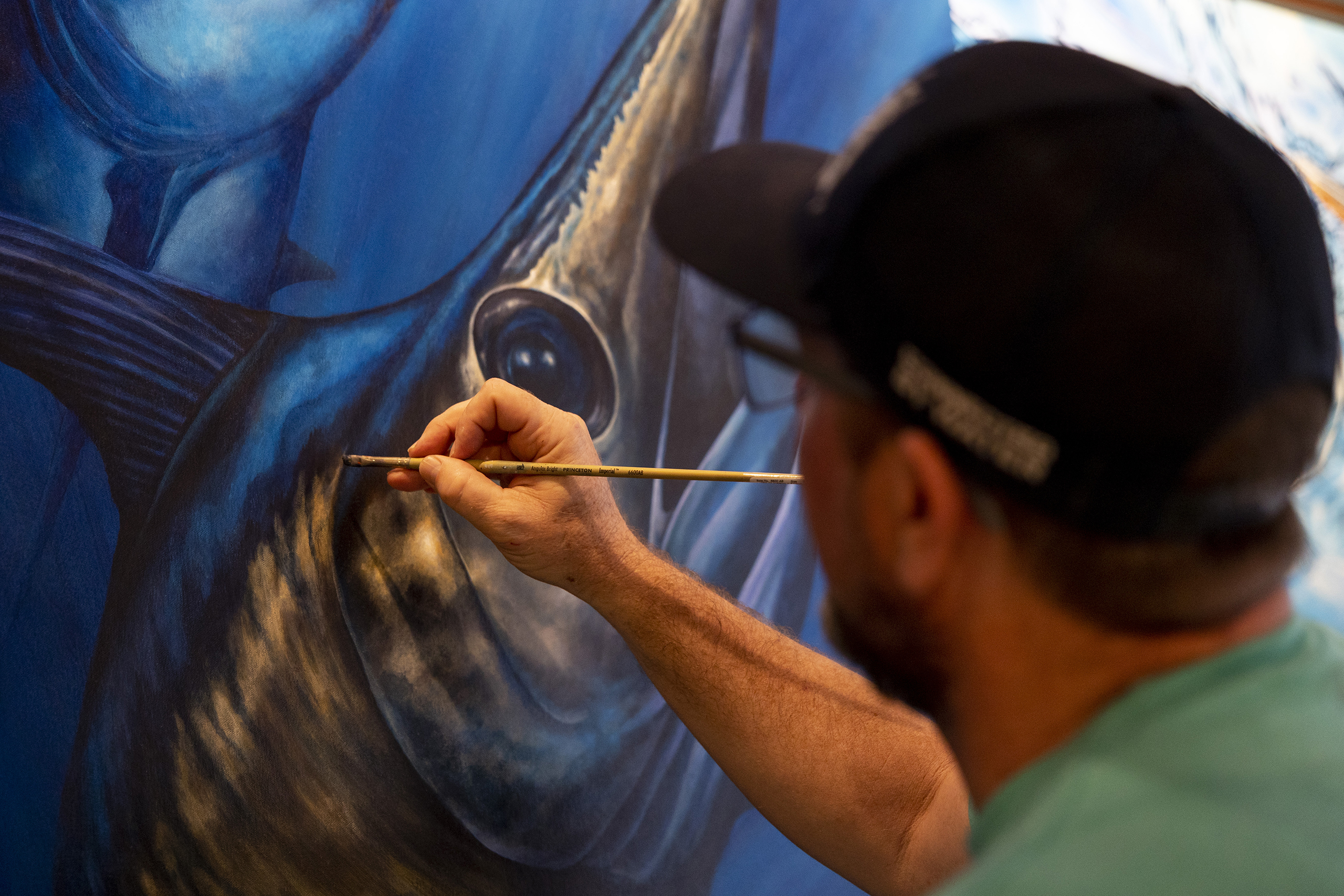 Dennis Friel paints details on a fish mural.