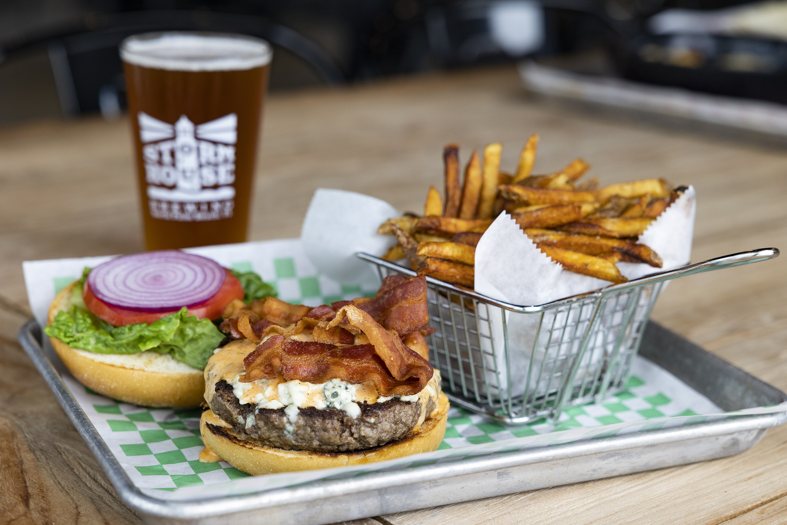 Bacon Cheese burger on a metal tray with fried and a pint of beer. Menu item at Stormhouse brewing in North Palm Beach, FL.