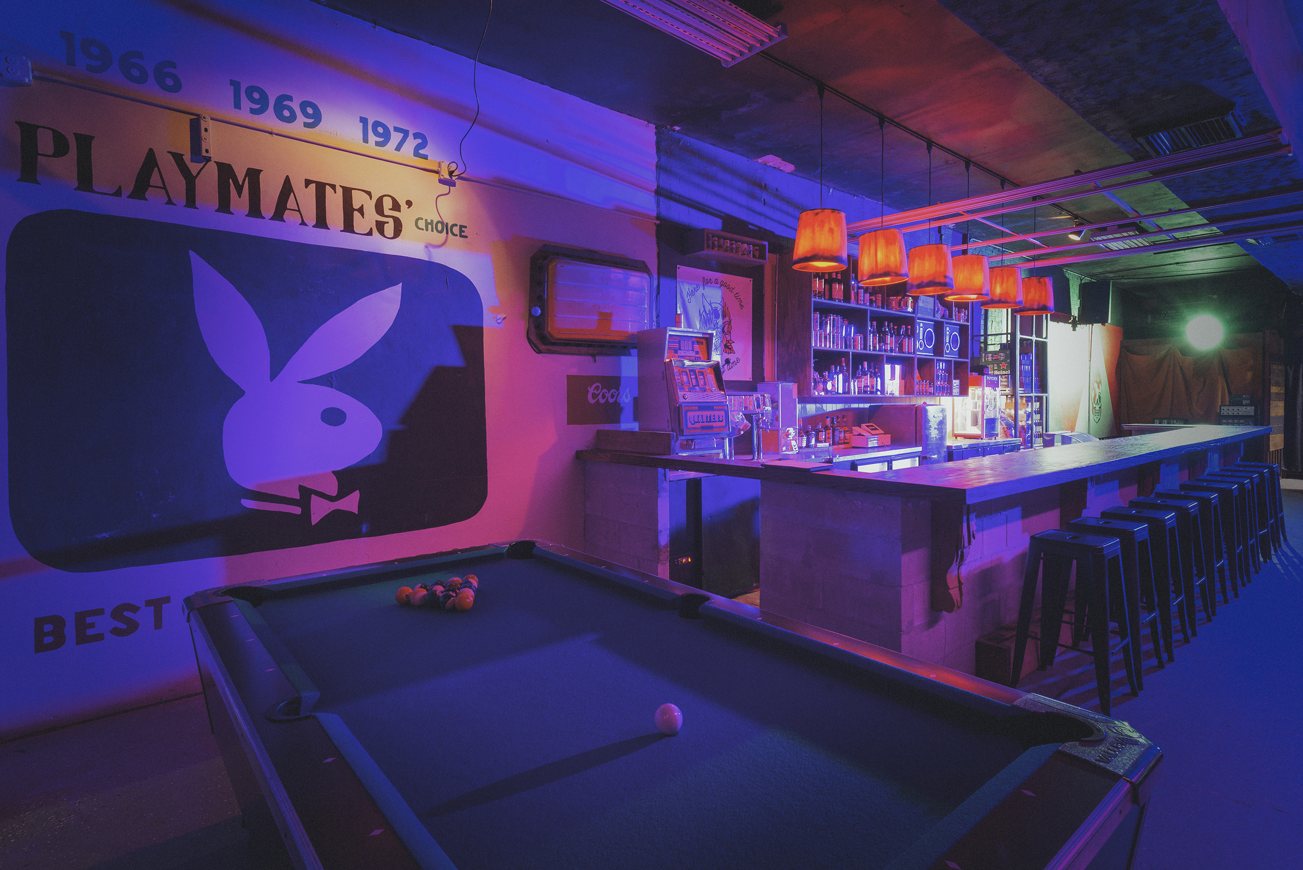 A wide angle of the moody interior of Tough Times Tavern in Pompano Beach. Complete with a pool table, PlayBoy Bunny wall art, and an expansive bar.