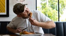 Chef Rick Mace taking a big bite out of his favorite dish, the smoked chicken, at Tropical Smokehouse in West Palm Beach, FL.