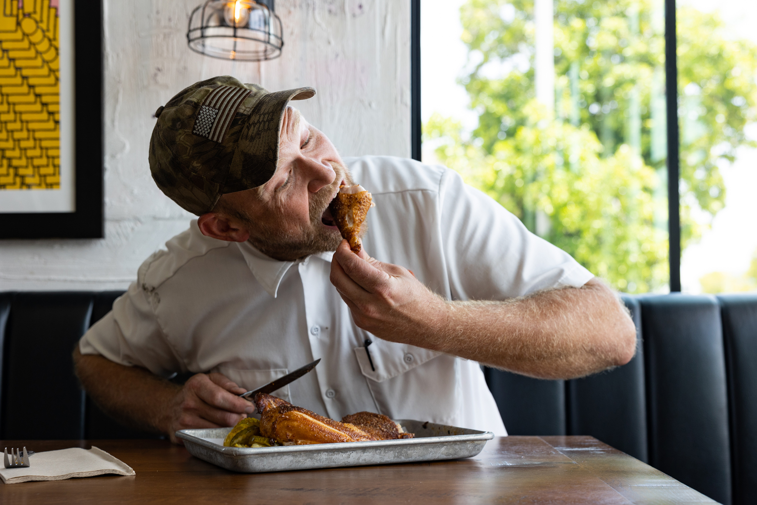 Chef Rick Mace taking a big bite out of his favorite dish, the smoked chicken, at Tropical Smokehouse in West Palm Beach, FL.