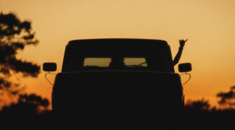 Sunset photo by Brian Hall of a hand throwing up a shaka outside of a truck.
