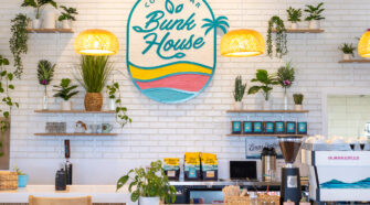 The front counter area of Bunk House, with the white Subway-tiled wall in the background decorated with the store's logo and various plants.