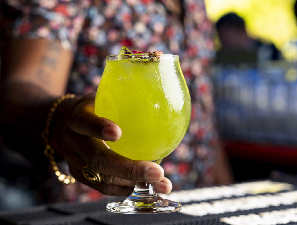 The green Heart Mocktail at Kapow! in a stemmed glass held by bartender Myles Robinson 