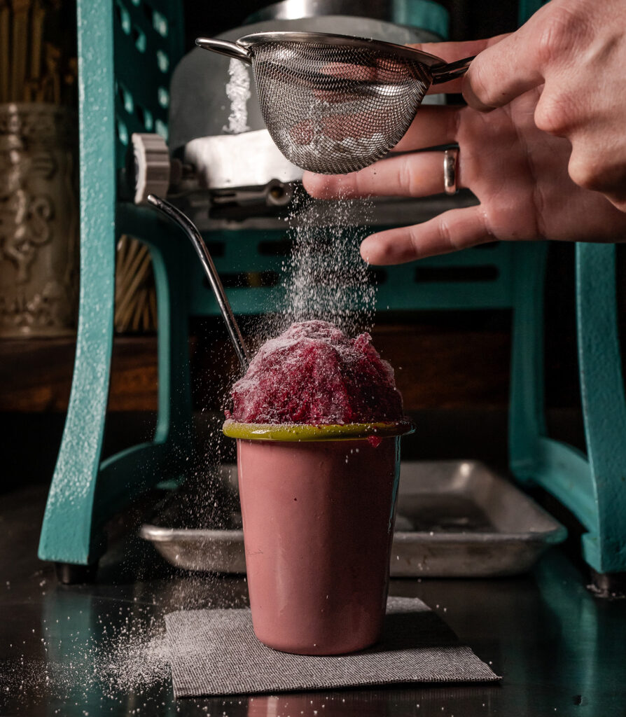 Huckleberry Coolada cocktail at Juicy Cocktail Bar in West Palm Beach. Purple cocktail, like a snowcone, with a dusting of sugar. 