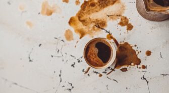 Spilled coffee and mug on white marble table. Coffee Cocktails feature.