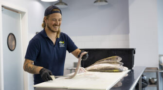 Reed Brand, fishmonger, filleting a fish inside Captain Clay and Sons.