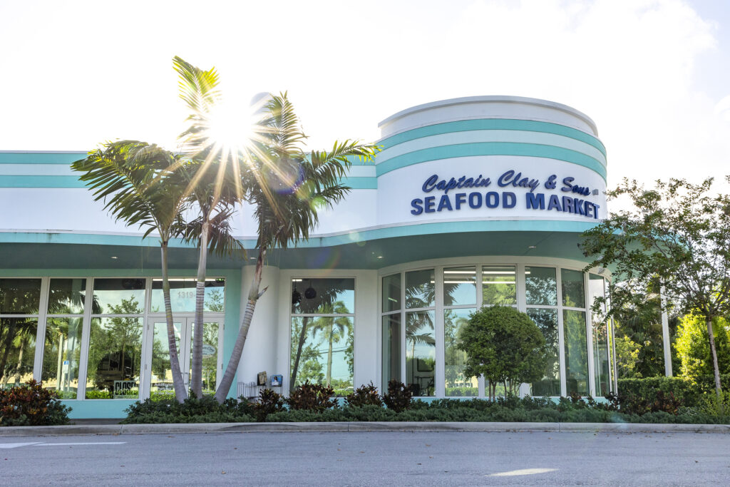 Exterior of Captain Clay and Sons in Delray. The sun backlights a retro, teal blue building. 