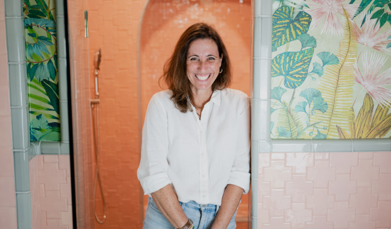 Lani Goodrich, creative ceramicist standing in front of her coral, handmade tiles.