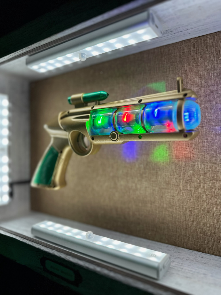 Multi media art piece by Damien Fitzgerald. The piece looks like a ray gun, with colorful lights in the barrel. 