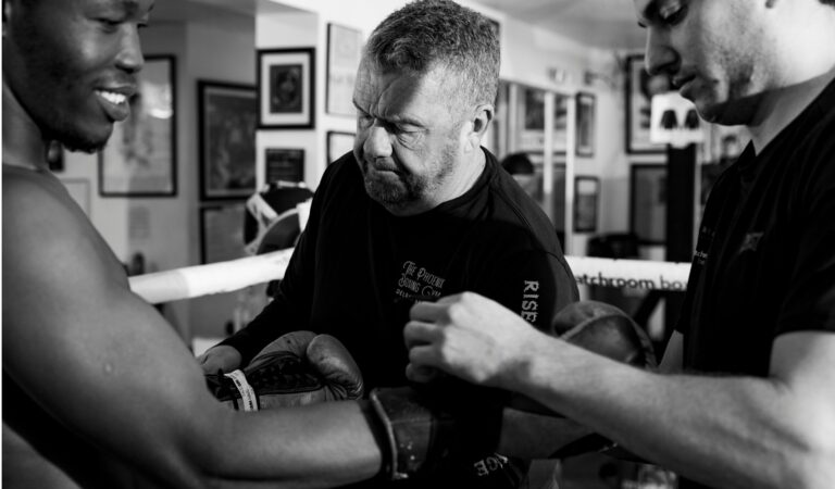 Black and white of owner of Phoenix Boxing in Delray, Michael Hockton, wrapping a student's hand before a match.