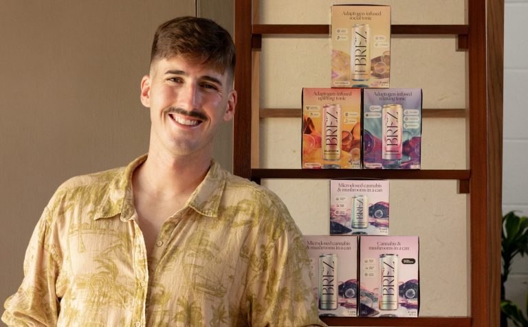 BREZ founder Aaron Nosbisch poses for a photo next to a shelf of BREZ products