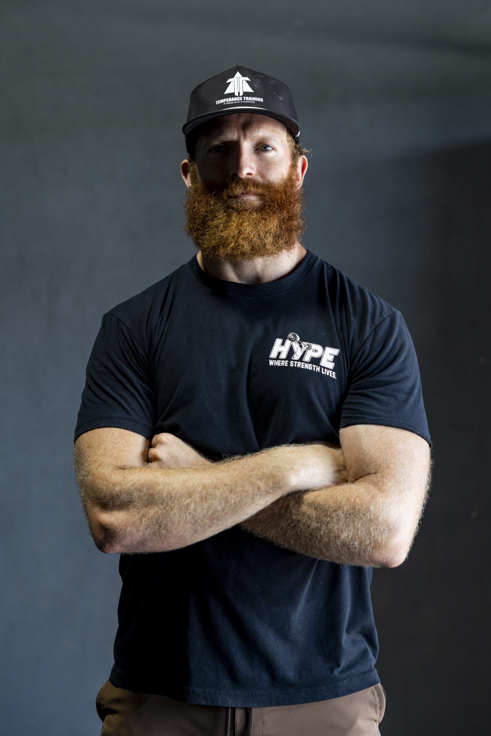 Rob Thomas, owner of CrossFit Hype, poses for a photo standing with his arms crossed. Rob wears a Temperance Training baseball cap and a CrossFit Hype T-shirt