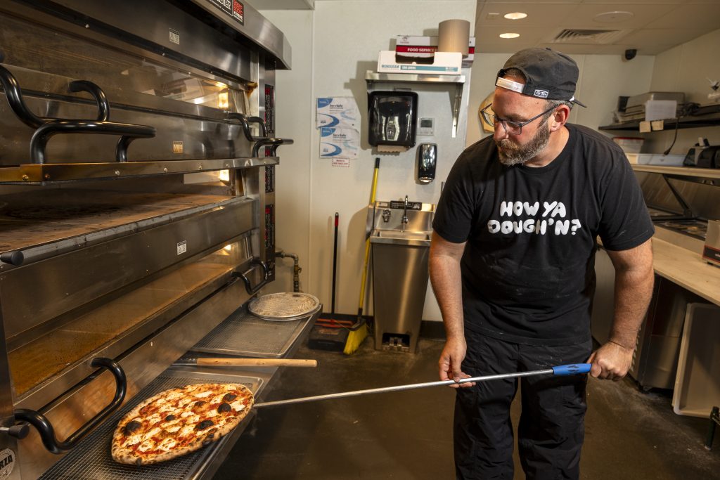 Garett Goodman putting pizza in the oven 